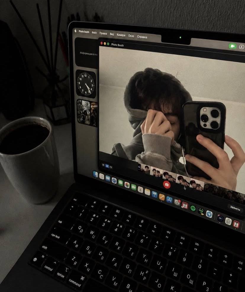 An intimate self-portrait reflected in a laptop screen beside a coffee cup.