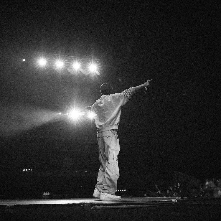 Phil Coutier seen from behind on stage, raising an arm towards the audience.